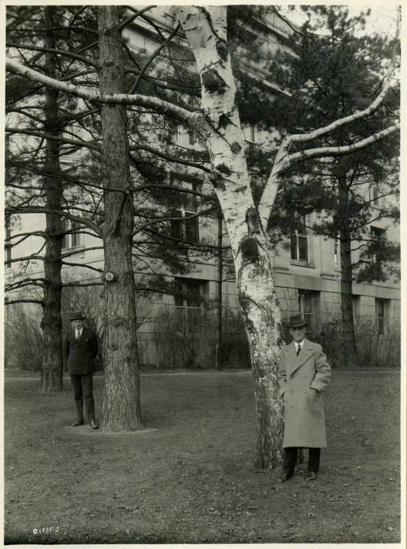 Two men standing by trees, December 08, 1925.