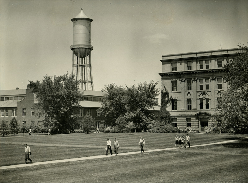 Students are walking on campus. Engineering Hall II (later known as Marston Hall) is on the right and the Marston Water Tower is in the background, Spring 1940.