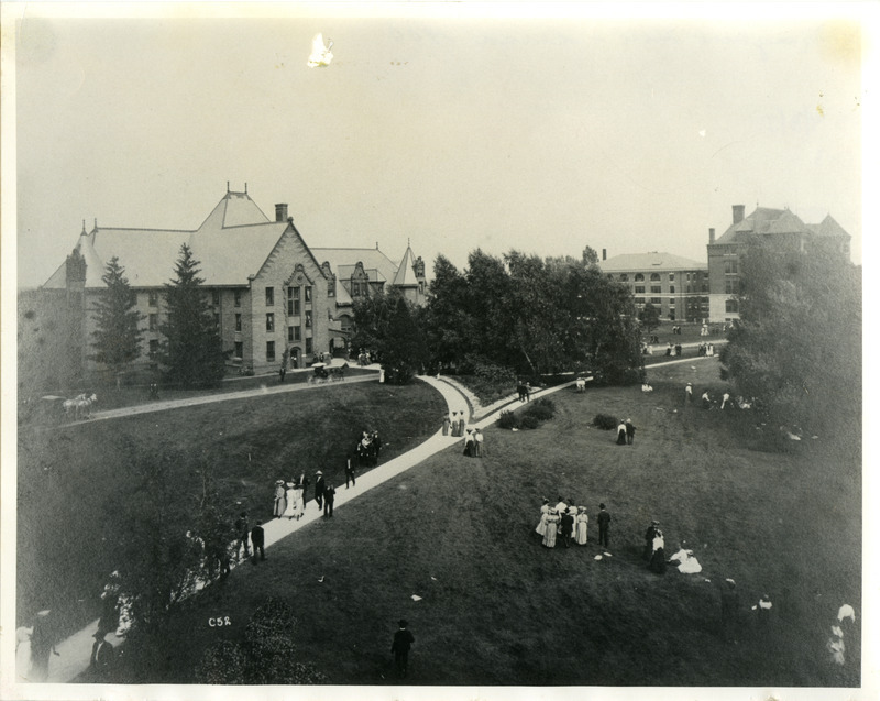 Two horse-drawn carriages are passing in front of Ladies Hall (later known as Margaret Hall). Botany Hall (later known as Carrie Chapman Catt Hall) is on the far right. The Quadrangle is behind Botany Hall, 1900.