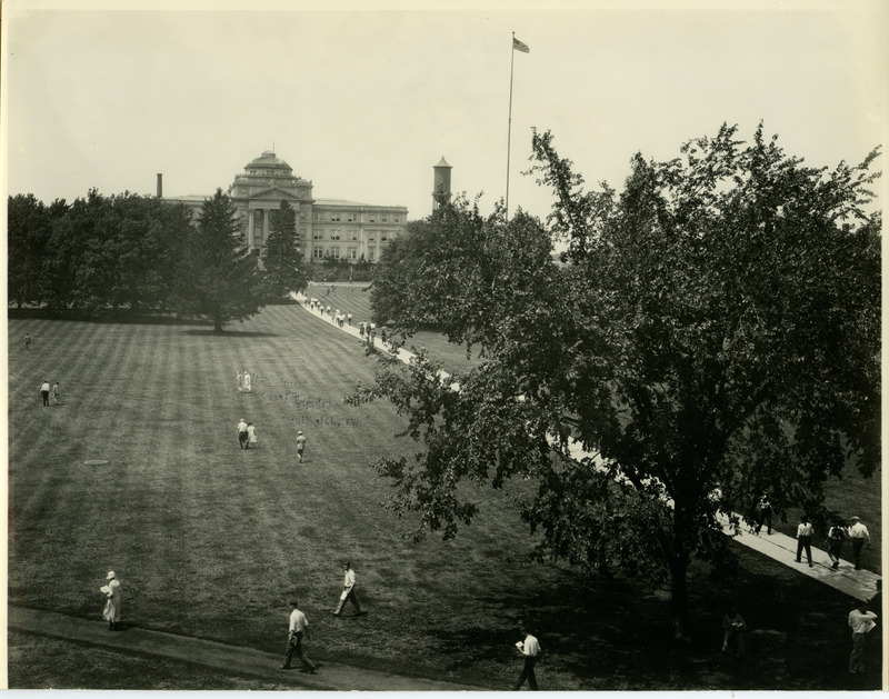 In this view of campus, taken after convocation, some people are walking toward Central Building (later known as Beardshear Hall). The top of the Marston Water Tower is visible to the right of Central Building, July 28, 1926.