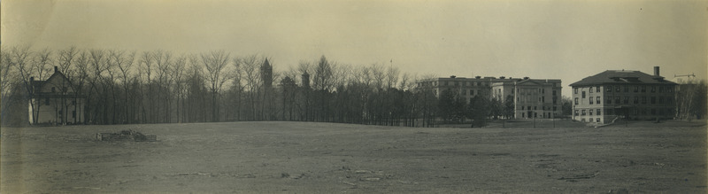 This panoramic view is looking northwest from the pasture behind Knapp's Woodruff Place. The house on the left belonged at the time to Lizzie May Allis. Viewed from left to right are Coover Residence, Agricultural Hall (later known as Curtiss Hall), and the Dairy Building. The tops of the Campanile, Central Building (later known as Beardshear Hall), and the Marston Water Tower are visible through the trees. The sheep pasture was the location for the women's dormitories in 1954.