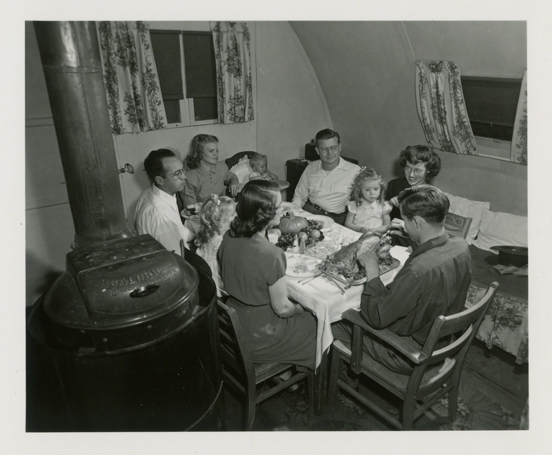 Adults and children shown at a cooperative potluck Thanksgiving Dinner in November 1948. Photograph was taken at Pammel Court, the then residency for married students.