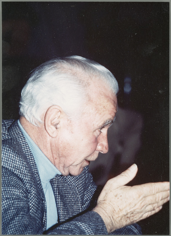 Earl O. Heady is shown in profile, speaking to someone while gesturing with his right hand, 1980s.