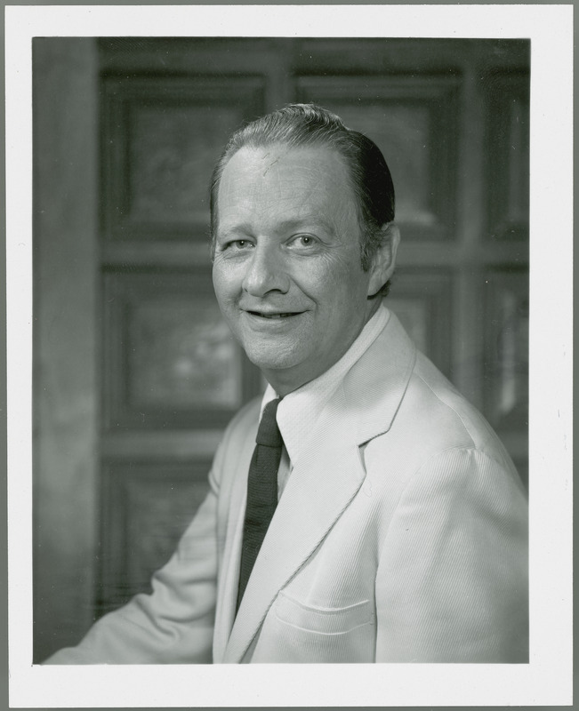 John Heer, Experiment Station Information Editor, is shown smiling against a background of square blocks in this portrait taken in 1975.