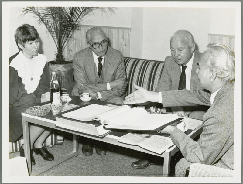 Earl O. Heady, in Hungary, gestures towards a bound printout on a coffee table with beverages, 1979. The woman translator sits opposite him on a chair, while J. Toth and a man sit on the adjacent sofa. Dr. Joseph Toth is Rector (President) of the Debrecen Agricultural University of Hungary.