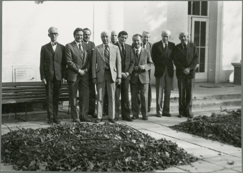 Earl O. Heady stands outside a building with nine professors from the Warsaw Agricultural University, Faculty of Agricultural Economics, 1979. They include J. Kosicki and T. Rychlik, and others with names beginning with R, W, C and B.