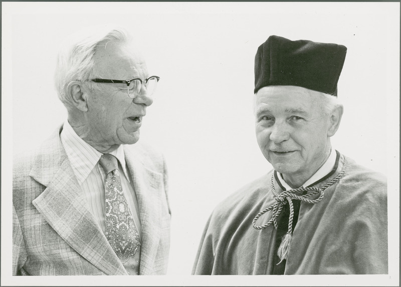 Earl O. Heady, in his Polish honorary doctorate academic robes, smiles at something emeritus Professor of Economics William Murray is saying to him.