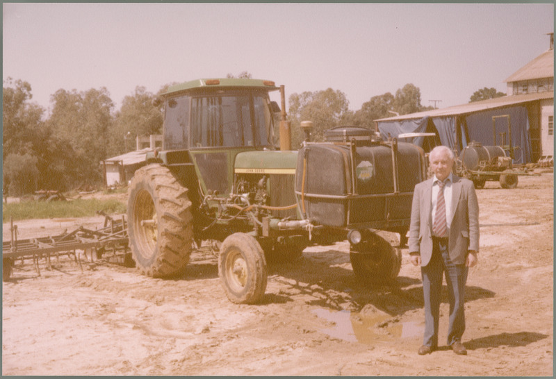 Earl O. Heady stands in front of a tractor at Kibbutz Na'an, Israel, March 19, 1983.