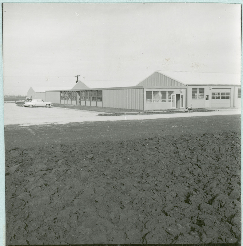 The Agronomy and Agricultural Engineering Research Center west of Ames is seen from across a plowed field, 1962.