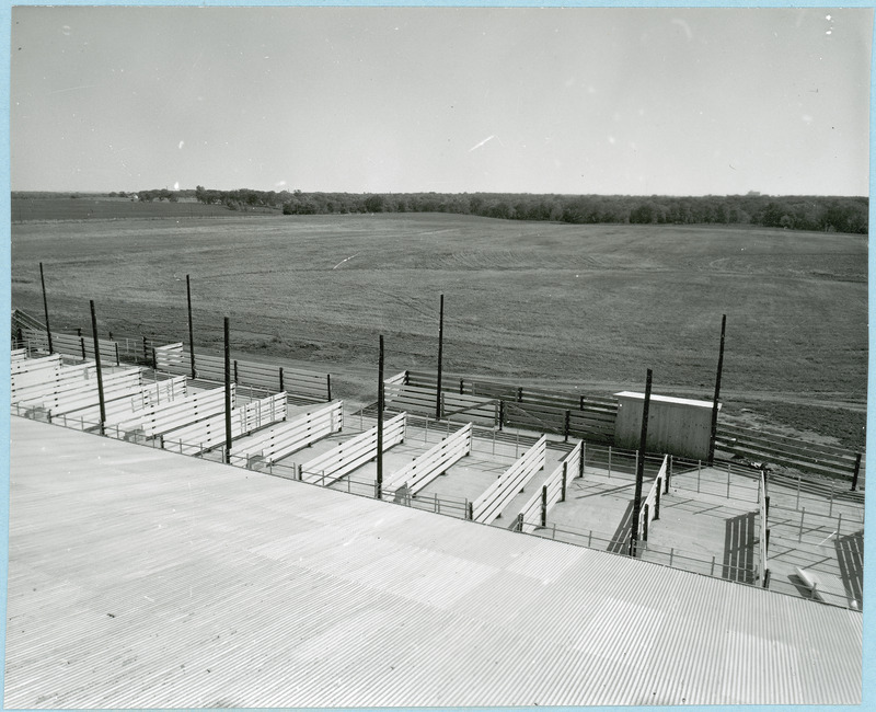 The Agriculture Experiment Station Nutrition Laboratory for beef cattle, located on a farm near Ontario, is shown from the corrugated roof looking down on the fenced pens towards an open field, 1955?.