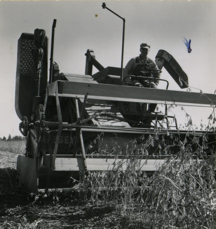 A farmer operates a self-propelled combine to harvest crops in Washington County, Iowa, shown in front close-up.