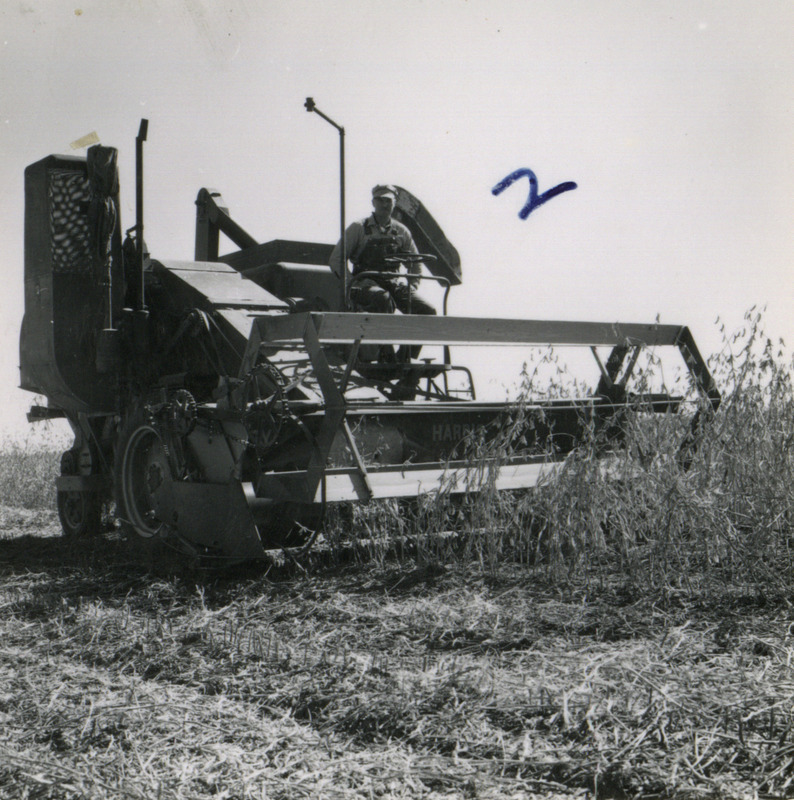 A farmer operates a self-propelled combine to harvest crops in Washington County, Iowa, shown in view from front.