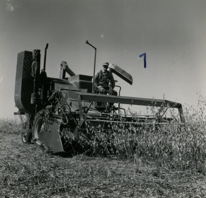 A farmer operates a self-propelled combine to harvest crops in Washington County, Iowa, shown in front close-up.