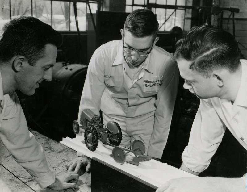 Dr. Clarence Bockhop (left) and two students observe a plain tillage linkage system with a model tractor.