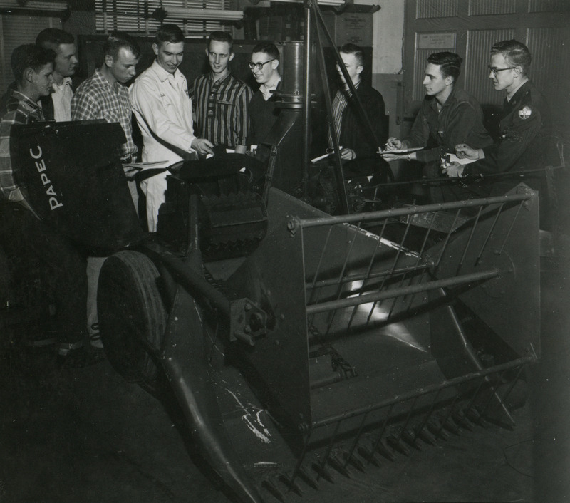 In the Power and Machinery Lab, a group of students observe a large piece of Papec agricultural equipment.