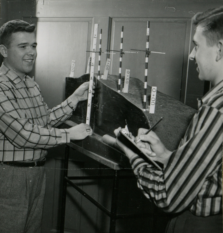 Agricultural engineers Kent Mitchell (left) and Gerald Hollander work out the relationship between the depth of trench and height if target on a tile drainage model.