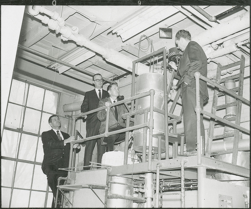 Thomas D. Wheelock and three other men examine a piece of equipment.