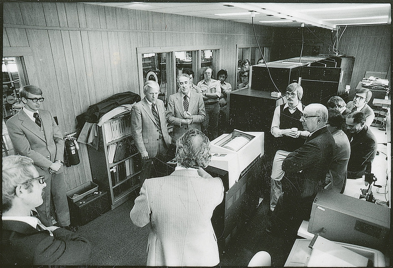 One person is talking to a group of individuals. The people are standing around a computer that General Mills presented to the Chemical Engineering Department.