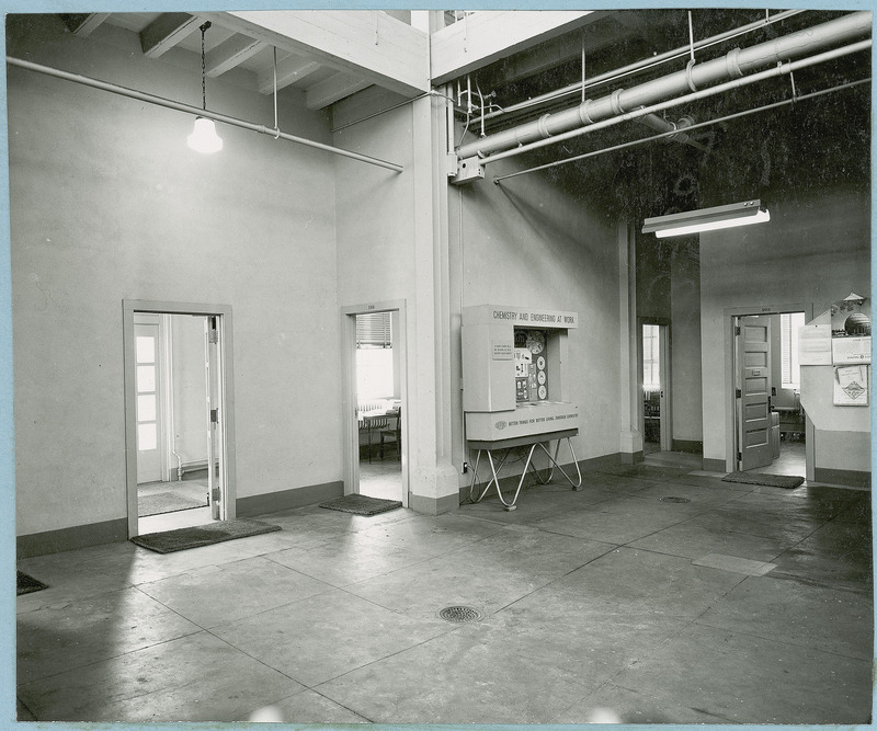 An almost bare Chemical laboratory has several doorways leading to other rooms. Along one section of the wall is a free standing exhibit entitled at the top: "Chemistry and Engineering at work." Along the bottom are the words, " DuPont better things for better living through Chemistry." the photograph appears in News of Iowa State, Feb. 1954.