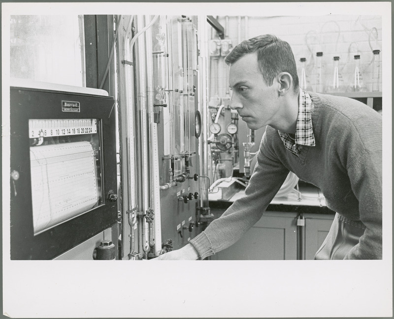 A male researcher checks a wall mounted monitor which is manufactured by Honeywell.