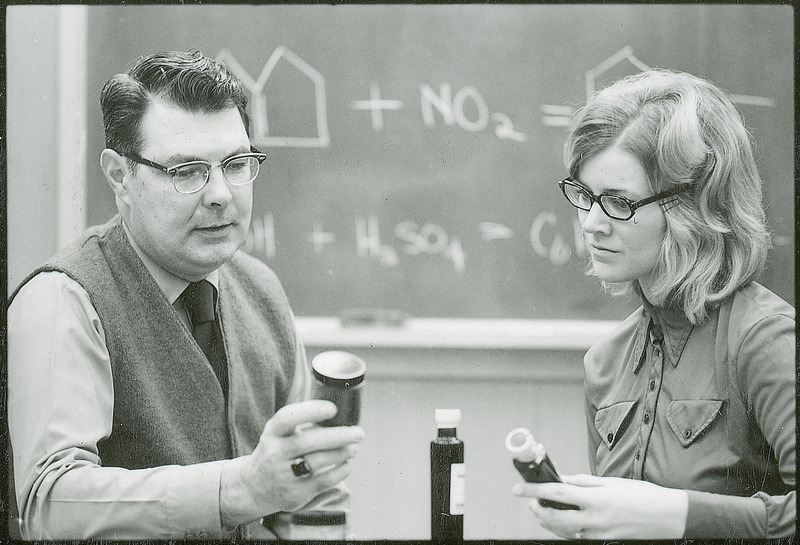 George Burnet is in discussion with another researcher. Both individuals are holding bottles filled with a substance.