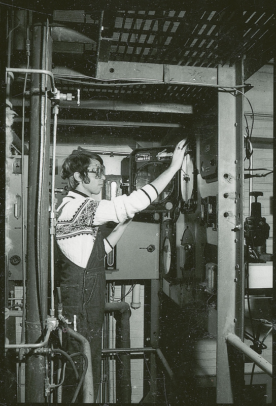 A researcher in safety goggles adjusts the controls on a piece of equipment.