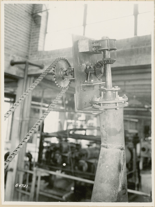 This is a close up view of a piece of equipment in a processing plant. A pulley and chain are to the left.