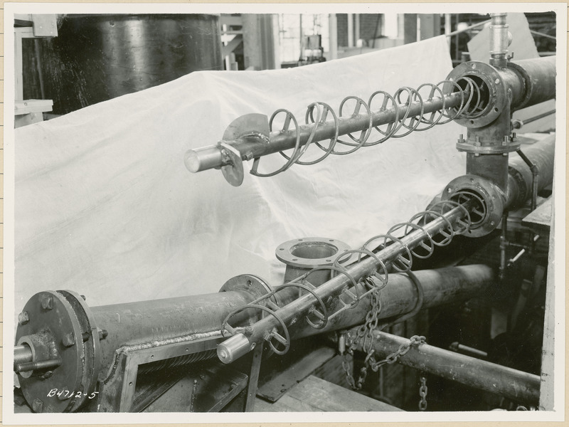 This is a piece of equipment in a processing plant. There is a white sheet behind the equipment. See photograph 840-01-03 for a close up view of part of this equipment.