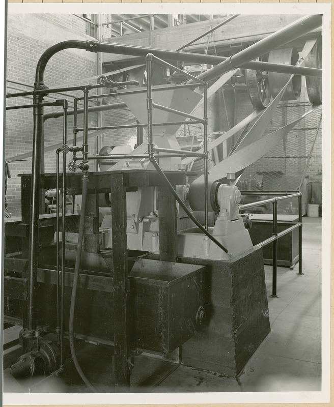 A rectangular bin sits empty at the base of this grinding apparatus.