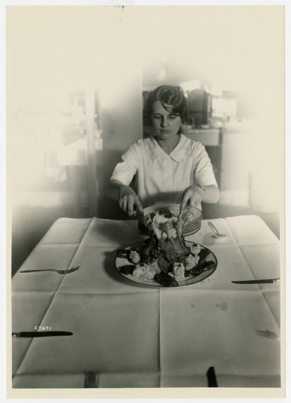 A woman is cutting a crown roast, probably part of a food and nutrition class.