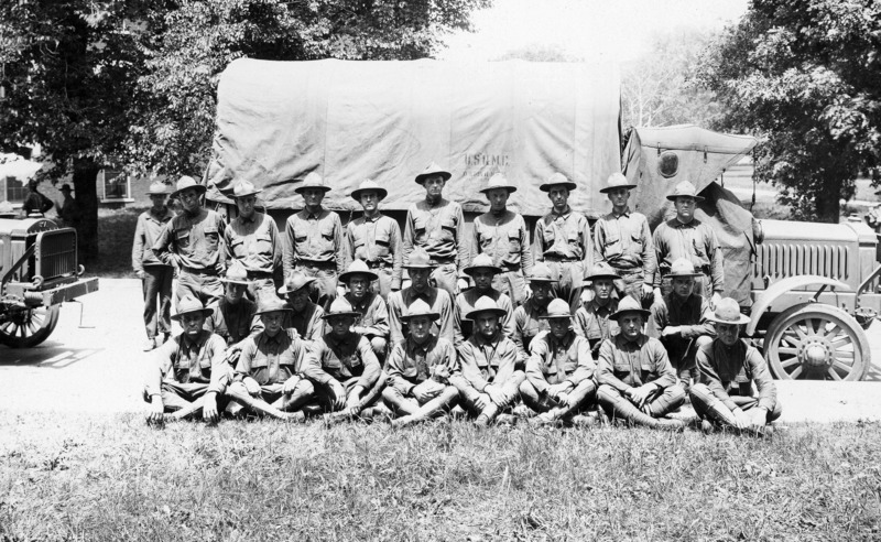 A unit of U.S. soldiers from Missouri known as "Haverhill's section, 1st detachment." Twenty-six men are posed for a photograph By a military transport vehicle. The truck's canvas cover is stenciled with the insignia "U.S.Q.M.C.".