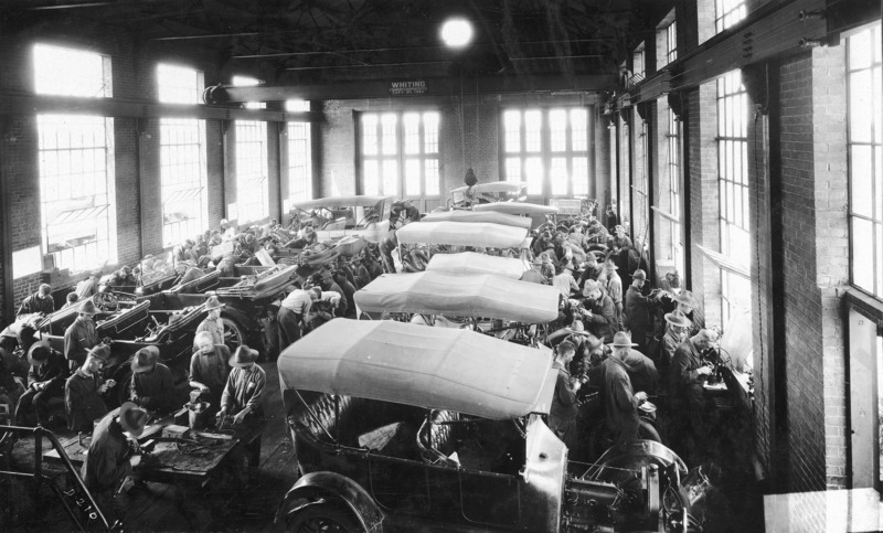 Military auto mechanics training. In an industrial building thirteen vehicles are being worked on by a large detachment of men.