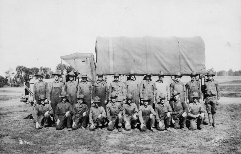 "Sergeant Purdy's section of the 39th military training detachment" posed for a formal portrait in front of a military transport truck. Twenty- two men in two rows, the front row kneeling, are posed for this photograph.