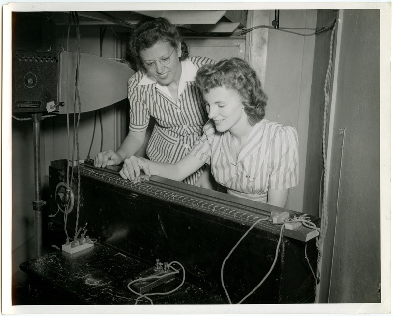 One cadette is watching another cadette operate a control system for a wind tunnel test.