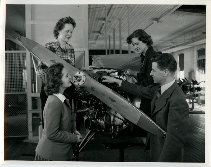 Professor Les Kelso is pointing out the propulsion system of a small general aviation airplane. These airplanes, sans wings, were in the Aeronautics Laboratory for purposes of visualization and illustration. The plane may be a Luscomb or a Taylorcraft.