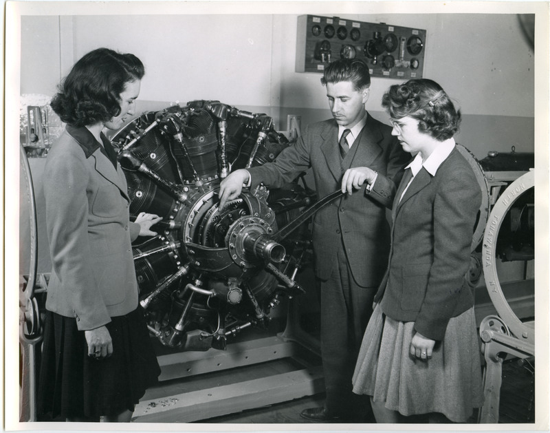 Professor Les Kelso is instructing two cadettes about an airplane engine.