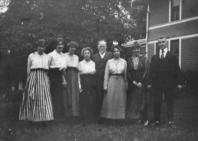 The Pammel family are posing for a photograph in front of their home on Duff Ave. in Ames, Iowa. Standing left to right: Doris M. Pammel, Lois H. Pammel, Violet E. Pammel, Mrs. Pammel, Dr. Pammel, Edna C. Pammel, Harriet M. Pammel, Harold E. Pammel.