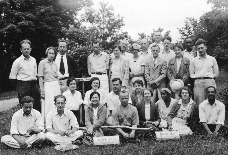 Students in the Botany Summer School are posing for a group photograph by a sign marking a "Nature Trail". Some students are standing and others are sitting in the grass.