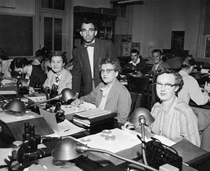 Dr. Duane Isely is working with three women from the Kansas State Seed Laboratory, Topeka, Kansas. Sitting left to right (excluding the two girls looking downward at the back): Mrs. Veda Phillips, Mrs. Leota Sprang, and Mrs. Stella Cailteux.