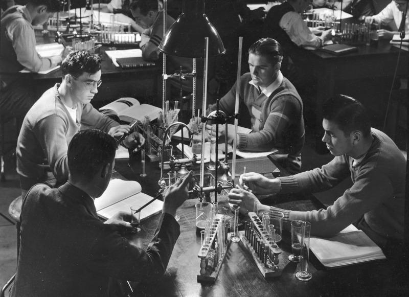 Male students in a physiology laboratory engaged in experimental exercises. "Students pry into the secrets of science in a physiology laboratory".