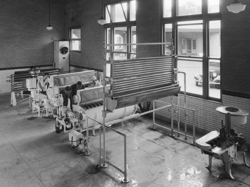 Unknown machinery in Veterinary Clinical Sciences facilities. Four men are shown peering into two vat-like structures.