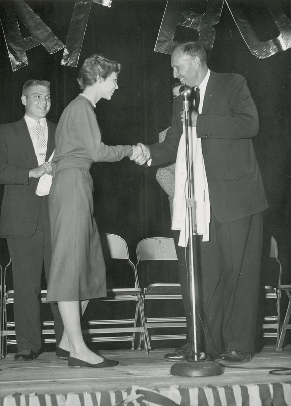 June Brandmill, homecoming queen, shakes the hand of an announcer at a Homecoming event.