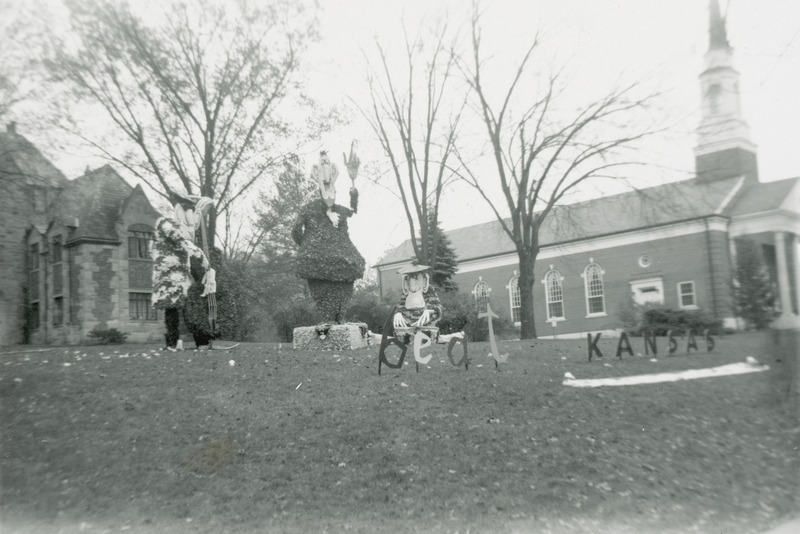 The three figures in Sigma Alpha Epsilon, Iowa Gamma Chapter's display are modeled on Don Martin's characters in Mad Magazine. There are two standing and one seated figure who is playing bongo drums. A sign in front of the display reads, "Beat Kansas.".