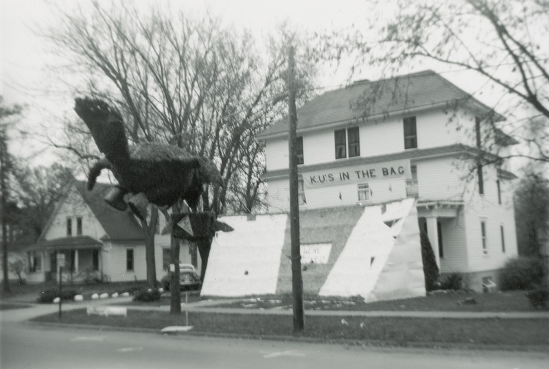 A Jayhawk figure is carrying a suitcase labeled, "Miami." It is in midair but is heading in a direct that will result in a crash into the ISU football stadium. A sign above the display reads, "K.U.'s in the bag.".