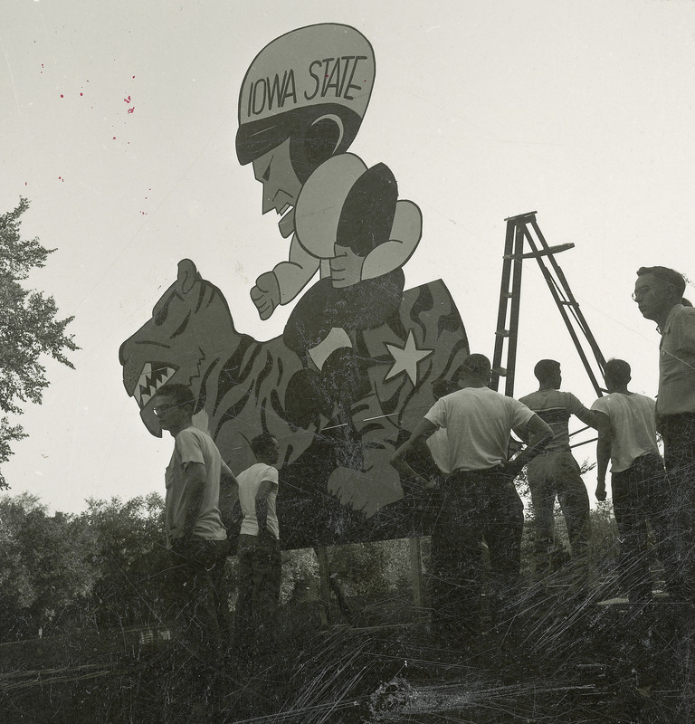 The Friley residence hall lawn display is being constructed. The display is a cut out figure of an Iowa State football player riding a tiger which represents the mascot of Kansas State University.