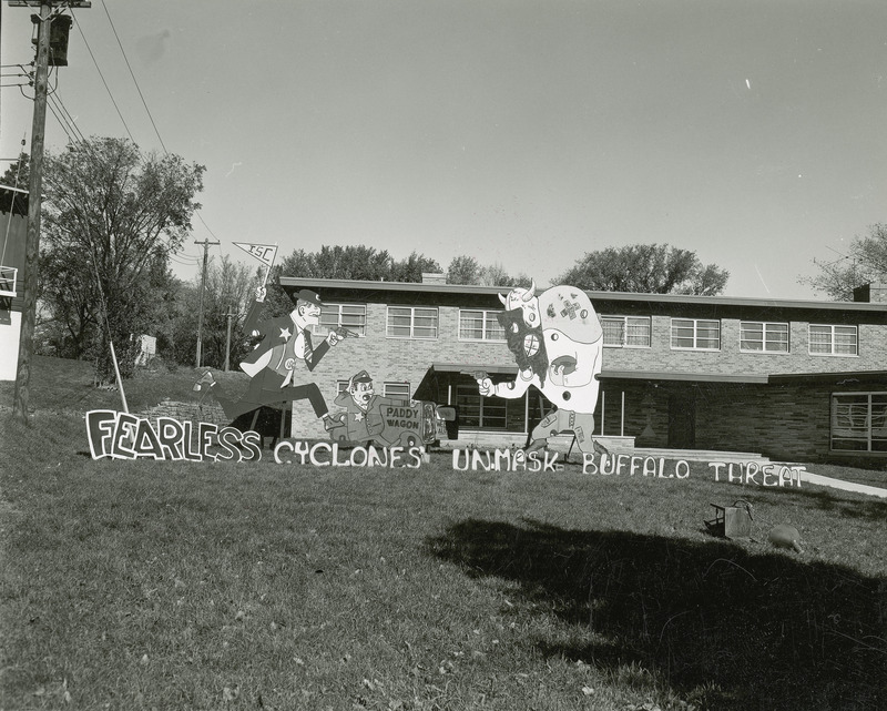 A figure reminiscent of Fearless Fosdick from the Li'l Abner comic strip runs towards a buffalo dressed in football gear. Both Fosdick and the buffalo point guns at each other.