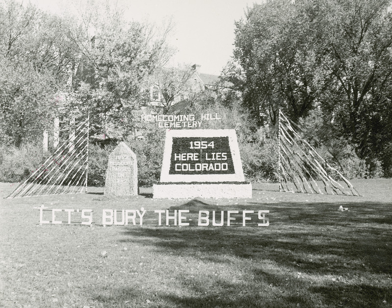 This lawn display won second place award in the Men's Residence Division for 1954. It features a two gravestones in the "Homecoming Hill Cemetery." The smaller gravestone is labeled, " 1953 Missouri passed on 13-6" in reference to the previous years homecoming football game. The larger stone is labeled, "1954 Here lies Colorado." .