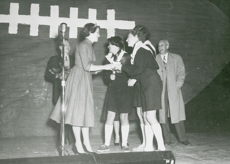 Homecoming queen Jody Dondore is presenting an award to a team of participants in the Rope-tying contest.