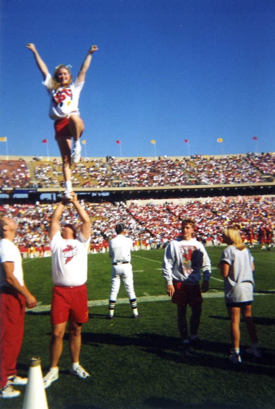 A cheerleader is being lifted up in the air at the Homecoming Game.