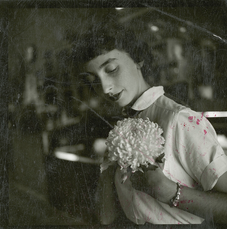 A girl is attaching a mum corsage to her blouse at Homecoming.